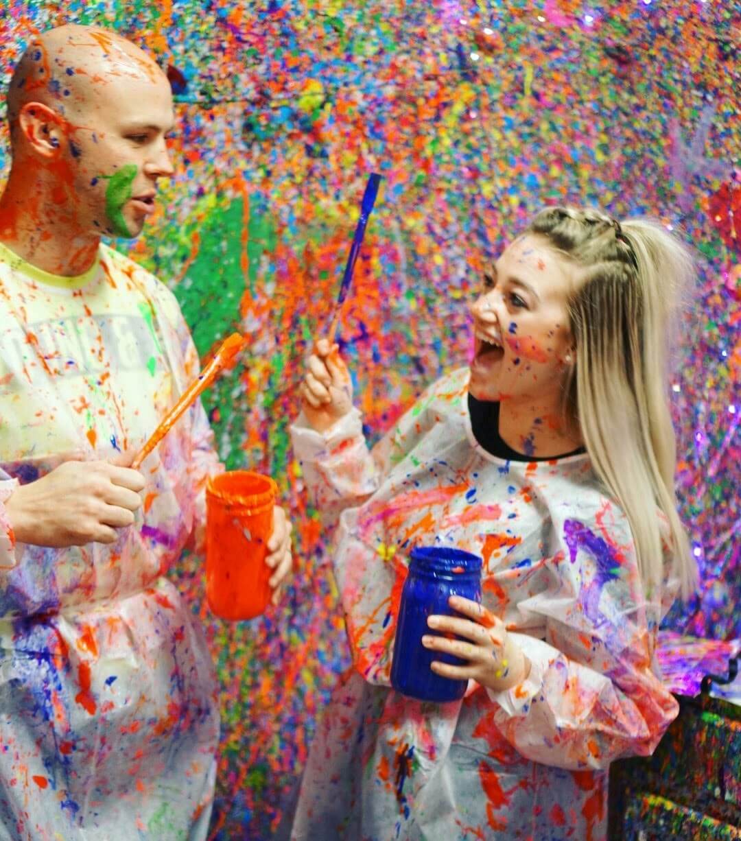A couple having fun splattering paint on each other in the Splatter Room